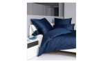 Mako-Satin Kissenbezug Colors in der Größe 15 x 40 cm und in der Farbausführung jeansblau, auf einem bett ebezogen mit der passenden Bettwäsche und weiteren Kissen