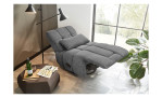 Relax-Sessel in grauem Cordstoff bezogen mit einem Zierkissen mit hochgestelltem Fußteil und zurückgefahrener Rückenlehne im Wohnzimmer.
