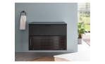 Waschbeckenunterschrank Dark mit einer Front in schwarz aus Holzwerkstoff und Glas und einem schwarzen Korpus. Auf einem dekorierten Hintergrund