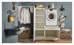 Stauraumschrank Laundry in weiß matt, mit einem Griff in Chrom matt. Auf einem dekorierten Hintergrund